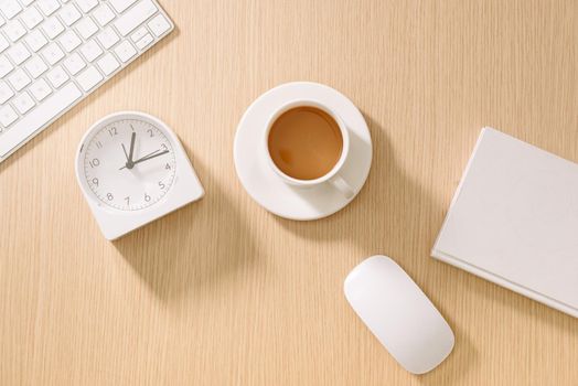 Modern white office desk with keyboard, mouse, notebook, clock and cup of coffee. Top view with copy paste. Business and strategy concept mockup.