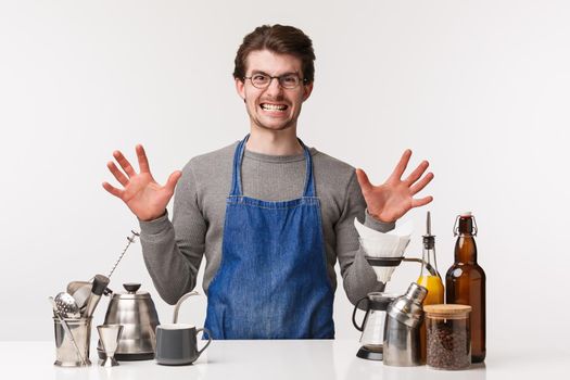 Barista, cafe worker and bartender concept. Portrait of pissed-off annoyed young man in apron making coffee feeling aggressive and irritated with rude clients, white background.