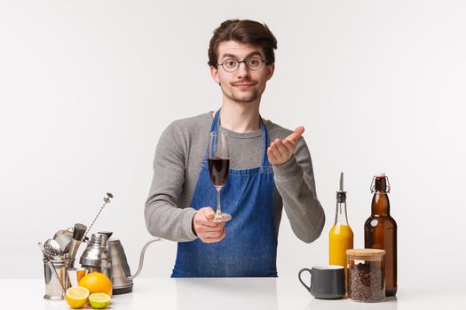 Barista, cafe worker and bartender concept. Portrait of good-looking male employee in apron working over bar counter giving customer glass of wine and presenting it like the best drink.
