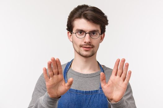 Slow down, take it easy. Close-up portrait of serious-looking confident young male coffee shop manager, employee trying calm person, show stop or easy sign, look camera white background.