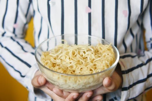 boy eating noodles in a bowl .