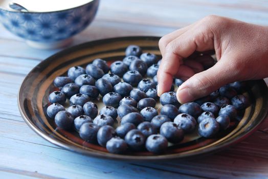 hand pick fresh blue berry from a plate .