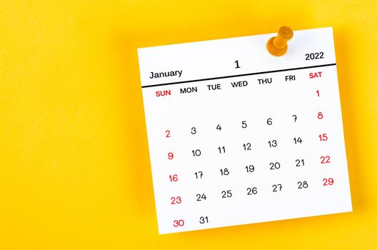 The January 2022 and wooden push pin on yellow background.