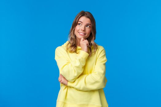 Dreamy and thoughtful female student planning her future after university, think about career opportunities, touch chin and smiling as look upper left corner, thinking, have things to ponder.