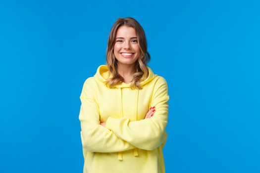 Lets get business. Confident smiling cheerful blond woman with white perfect smile, cross hands chest ready for tasks, listen to boss instructions, standing yellow hoodie over blue background.