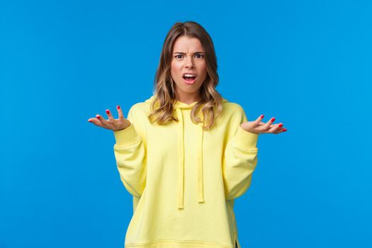 Frustrated and displeased confused young blond girl shrugging, looking at camera with disagreement and bothered expression, hear nonsense, have argument cant understand what happening.