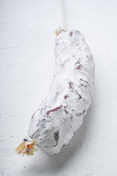 Salami sausage salchichon on white textured background.