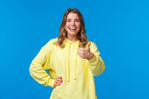 Very good, nice job. Girl praises friend for making great project, smiling satisfied show thumb-up and nod in approval, agree or like plan, standing pleased over blue background.