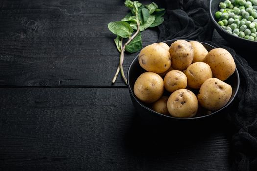 Baby whole potatoes, on black wooden background with copy space