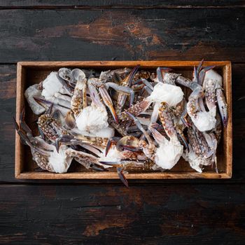 Frozen raw blue swimming crab meat set, in wooden box, on dark wooden background