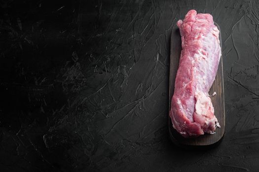 Raw pork fillet tenderloin. Fresh meat set, on wooden cutting board, on black stone background , with copyspace and space for text