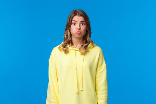 Silly and cute blond female pouting, hold her breath as promise being silent, dont tell anyone what happened or hiding secret, standing blue background, cant say anything.