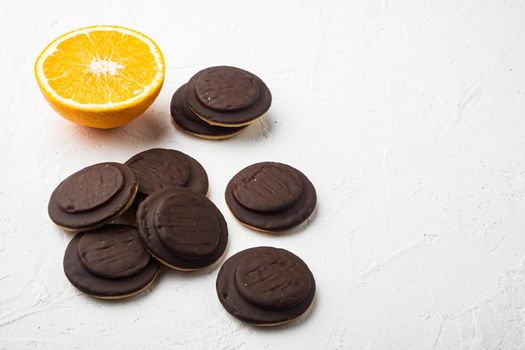 Biscuit filled with orange, topped with chocolate set, on white stone table background, with copy space for text