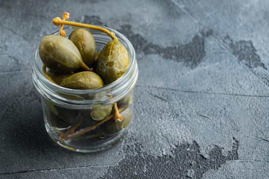 Capers, marinated in oil, on gray background with copy space for text