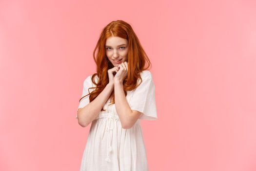 Relationship, seduction and love concept. Cute kawaii young redhead woman in white dress, acting silly and lovely, squirm on floor and looking coquettish from under forehead, blushing.