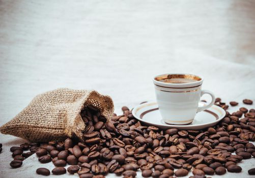 Coffee cup and beans on a biege burlap background. roasted coffee beans