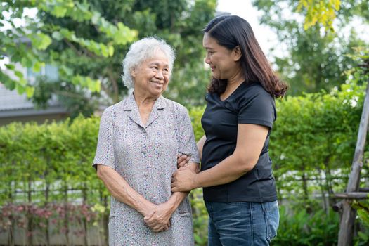 Asian elderly woman with caregiver daugther walking and hug with happy in nature park.