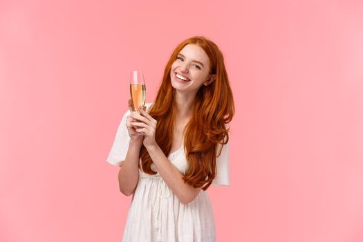 Carefree, excited cute redhead woman celebrating birthday, attend fancy party, wear white dress, laughing as discussing something with friends, raising glass champagne, drinking for success.