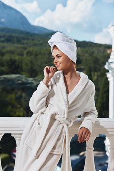Portrait of gorgeous woman in a white robe on the balcony bit on green nature unaltered. High quality photo