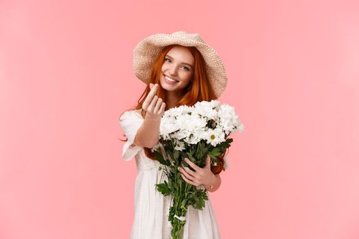 Love, relationship and celebration concept. Cute and silly charismatic redhead girlfriend express care and tenderness, receive beautiful bouquet flowers, holding it and making heart korean gesture.