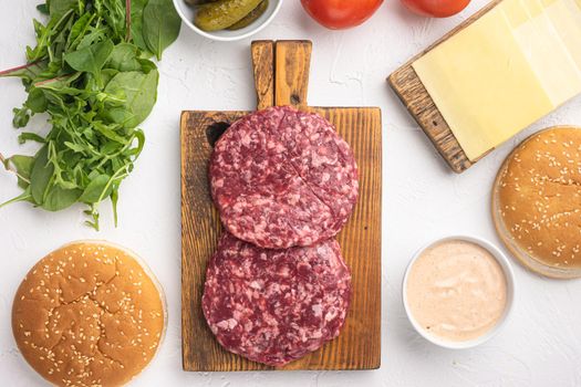 Raw Ground beef meat Burger steak cutlets with ingredients and buns set, on white stone background, top view flat lay