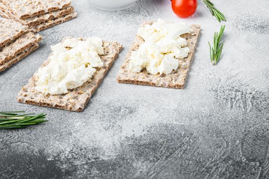 Fresh rye crispbreads with cream cheese set, on gray stone table background, with copy space for text
