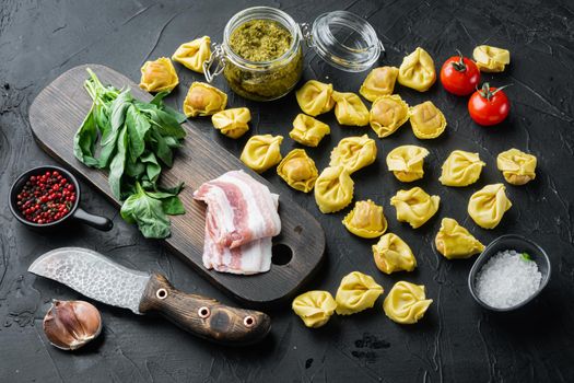 Raw homemade Tortellini with cured ham set, on black background
