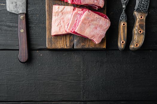 Short Ribs Bone In stew set, and old butcher cleaver knife, on black wooden table background, top view flat lay, with copy space for text