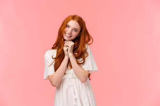 Cuteness overload. Silly kawaii redhead european girl with lovely gaze and grin, tilt head, begging something, asking buy cute thing in store, smiling cheerful, standing pink background.