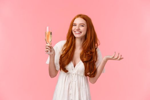 Lovely charismatic bride feeling happy and joyful, celebrating best day her lfie, looking camera amused, smiling raising glass champagne, drinking and partying, standing pink background.