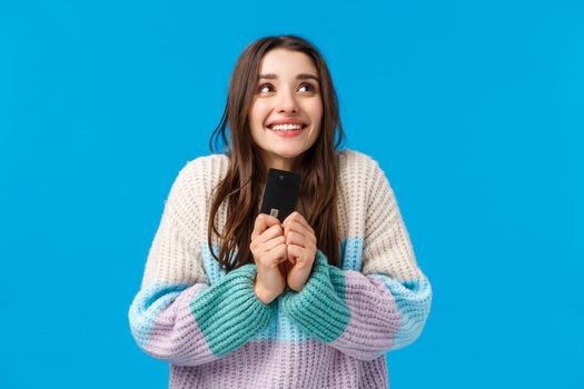 Dreamy and upbeat, thoughtful young woman dreaming how she will spend all money cashback, placed cash deposit to save-up, holding credit card, imaging something lovely, smiling.