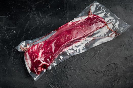 Sirloin beef steak in vacuum packaging. Market pack set, on black stone background, with copy space for text