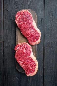 Sirloin steak, uncooked beef meat cut, on black wooden background, top view