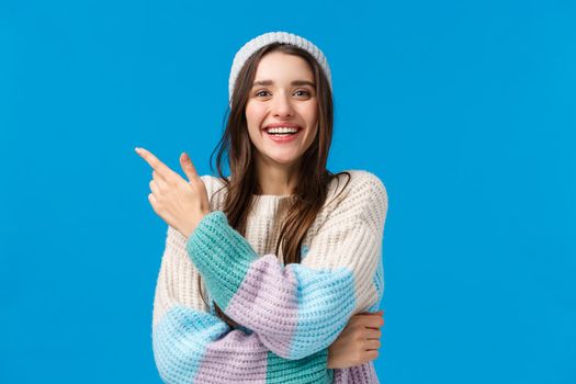 Shopping, sales and winter holidays concept. Cheerful, lovely european brunette woman with pretty smile, pointing upper left corner and smiling looking camera telling about amazing discount offer.