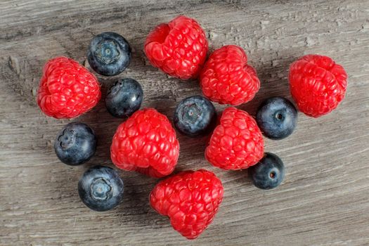 Tabletop view on couple of raspberries and blueberries mixed.