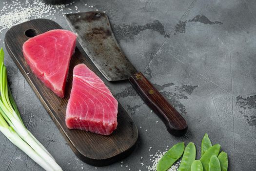 Raw tuna fillet. Seafood with sugar green pea, sesame and ingredients set, on wooden cutting board, and old butcher cleaver knife, on gray stone background , with copyspace and space for text