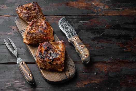 Tender cooked ribs in a delicious, rich sauce set, on old dark wooden table background, with copy space for text