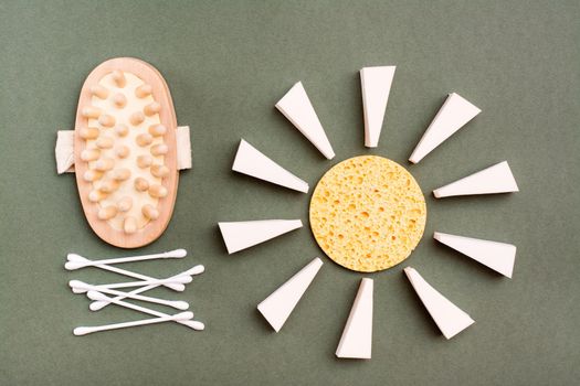 Personal care items. Bathroom set - massager, sponges and cotton swabs on a green background