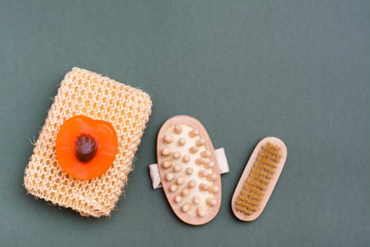 Body care. Washcloth, brush, massager and handmade soap on a green background.