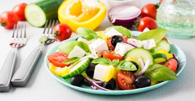 Fresh homemade greek salad with basil leaves on a plate and ingredients for cooking on the table. Domestic life. Web banner