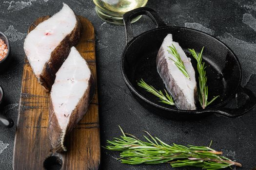 Raw halibut set, with ingredients and rosemary herbs, on black dark stone table background
