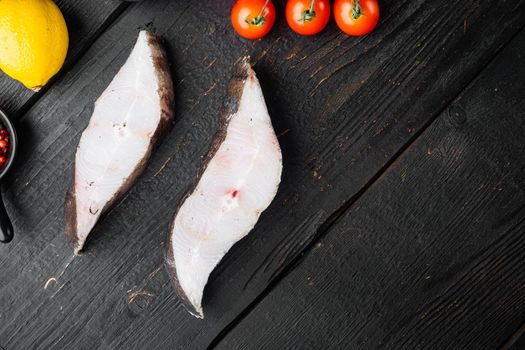 Raw halibut saltwater fish steak set, with ingredients and rosemary herbs, on black wooden table background, top view flat lay, with copy space for text