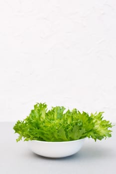 Fresh green lettuce leaves in a bowl on the table. Healthy eating. Copy space. vertical view