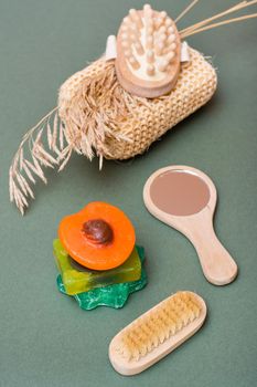 Body care. Different types of handmade soap without additives, washcloth, massager and brush on a green background. Vertical view