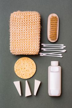 Body care. Bathroom set - washcloth, shampoo, sponges, cotton swabs and a brush on a green background. Vertical view