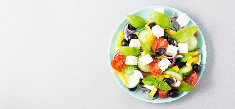 Fresh homemade greek salad with basil leaves on a plate on the table. Domestic life. Top view. Copy space. Web banner