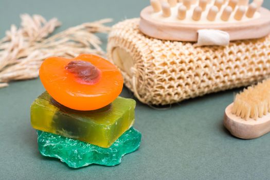 Body care. Different types of handmade soap without additives, washcloth, massager and brush on a green background. Close-up