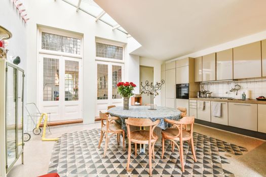 Chic dining room with round table with tablecloth and wooden chairs and black and white floor