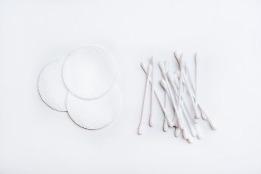 Several clean cotton pads and cotton swabs on a white background. Top view
