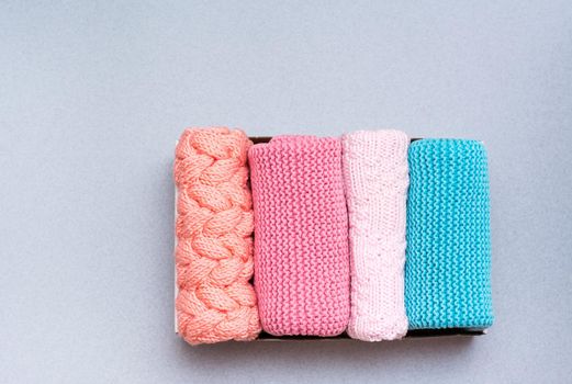 Organization and order. Knitted clothes lie neatly folded in a box on a gray background. Top view